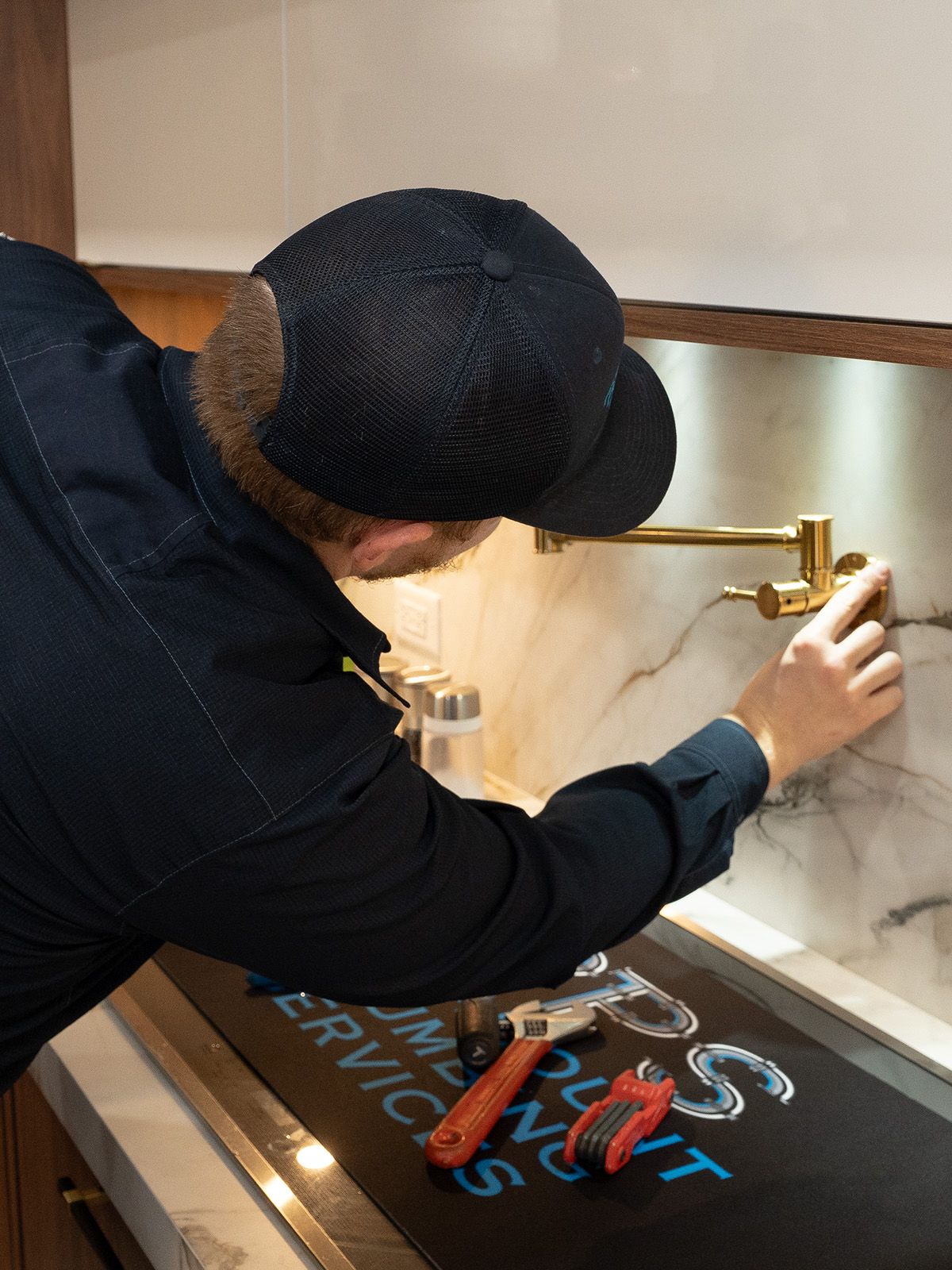 Paramount's plumber installing wall mount faucet on kitchen wall