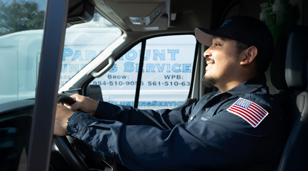 A plumbing service driver smiling while driving a service van.