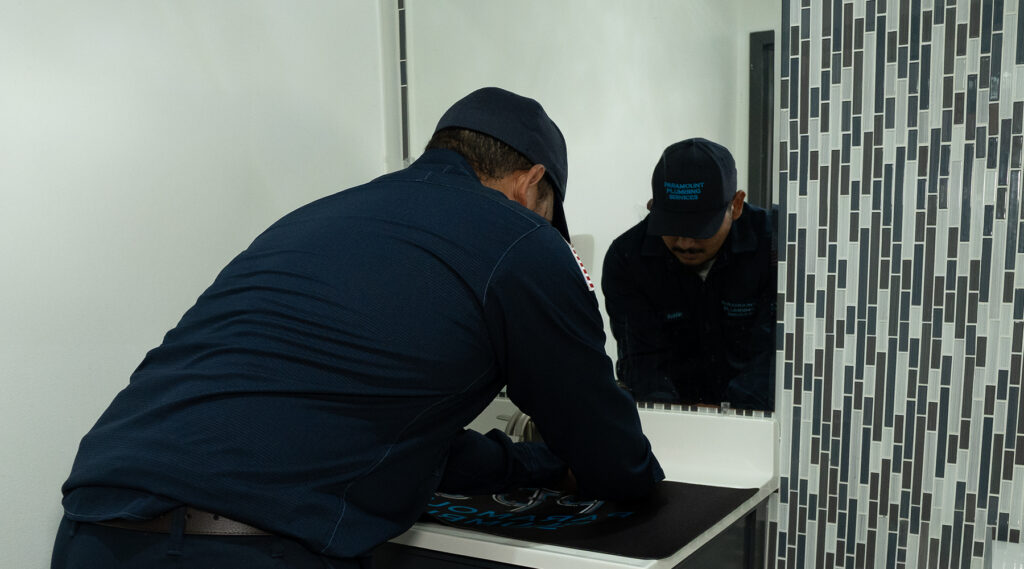 Plumber fixing sink faucet in bathroom