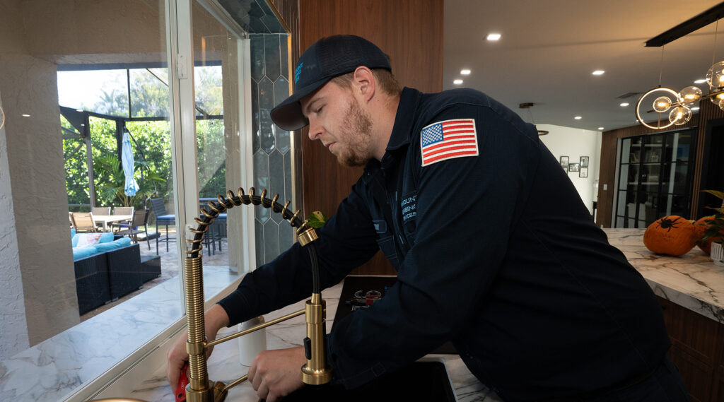 Paramount plumber installing a gold kitchen faucet