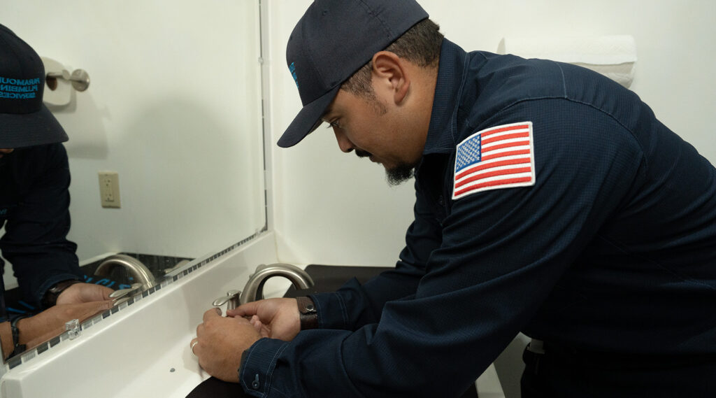 Paramount plumber installing brushed nickel bathtub faucet in white bathroom