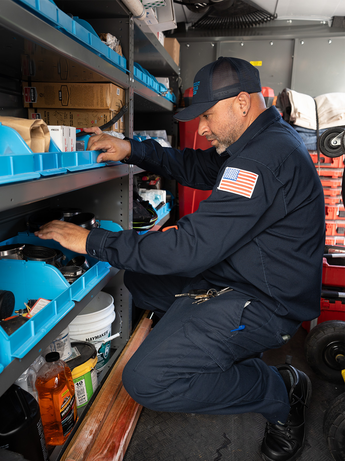 A technician organizing tools in a service vehicle's storage shelves.