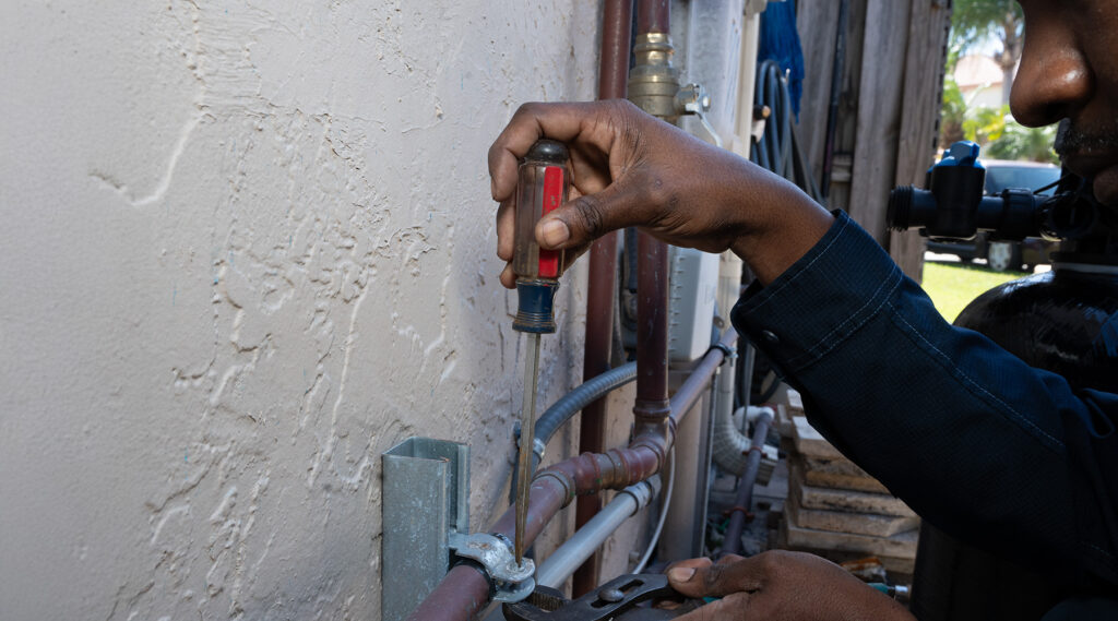 Paramount's plumber using a screwdriver to repair plumbing pipes.
