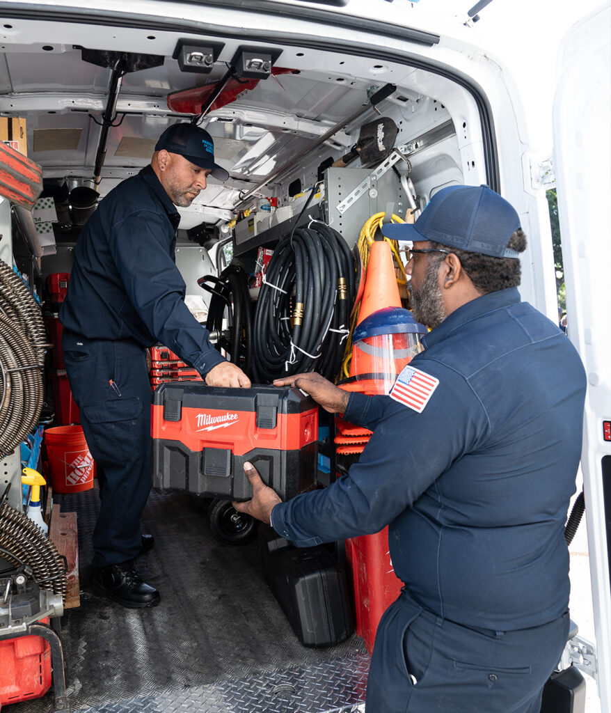 Two technicians loading tools into a service van, showcasing organized equipment.
