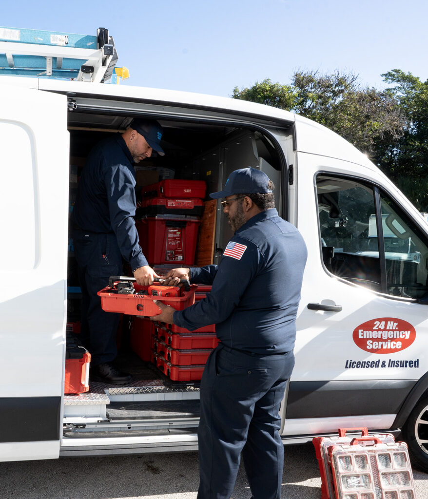 two plumbers holding red toolbox from work van