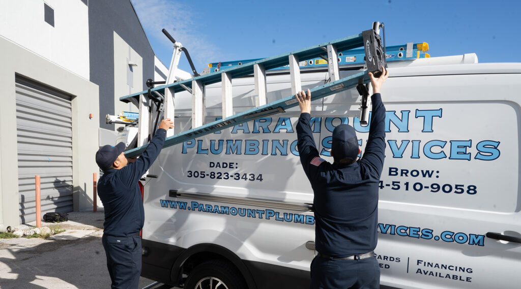plumbers putting ladder on top of work van
