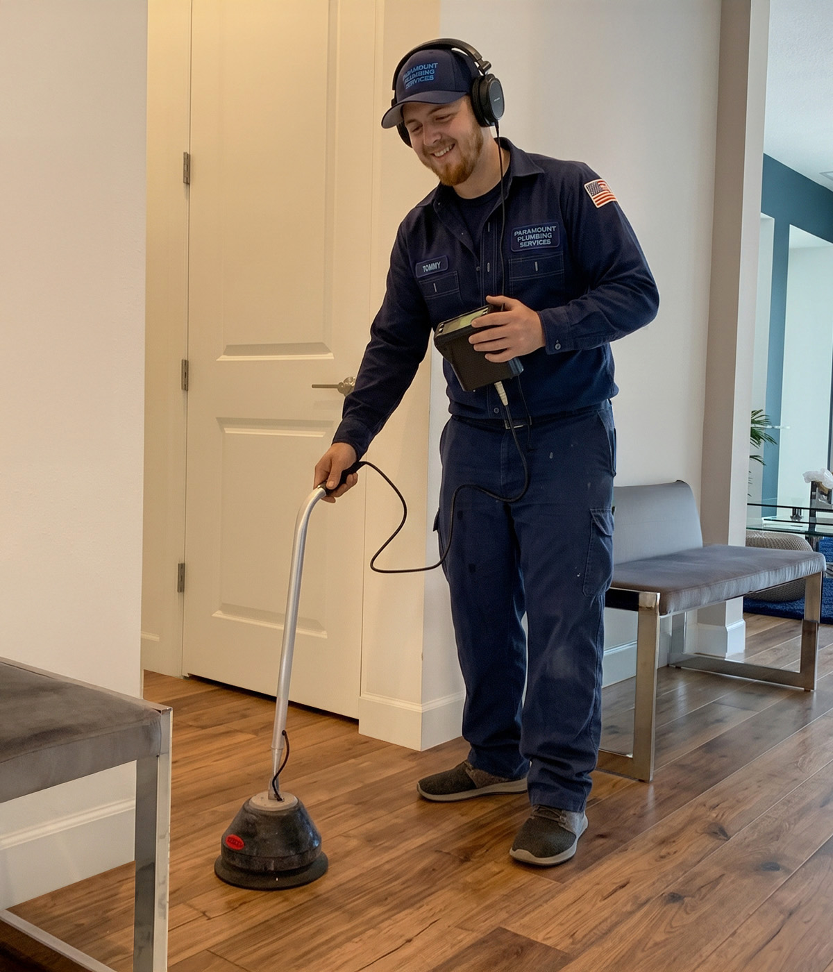 Plumber using electronic leak detection equipment on floor indoors