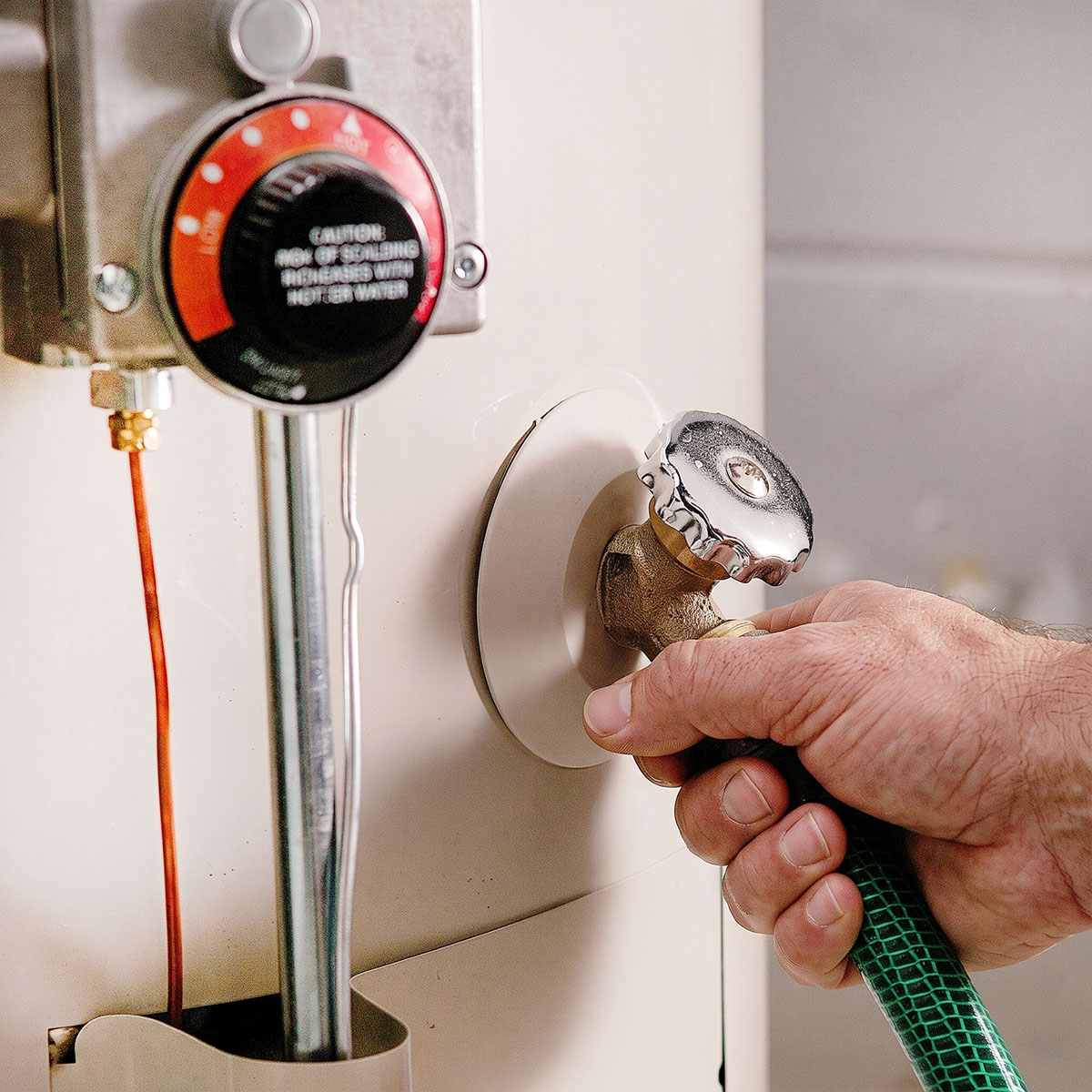 Paramount plumber attaching garden hose to water heater tank drain valve